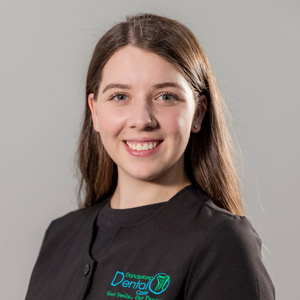 Professional female staff member with long brown hair smiling in a black uniform at Dandenong Dental Care.