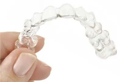 A hand holding a clear orthodontic aligner tray used for discreet teeth straightening at Dandenong Dental Care.