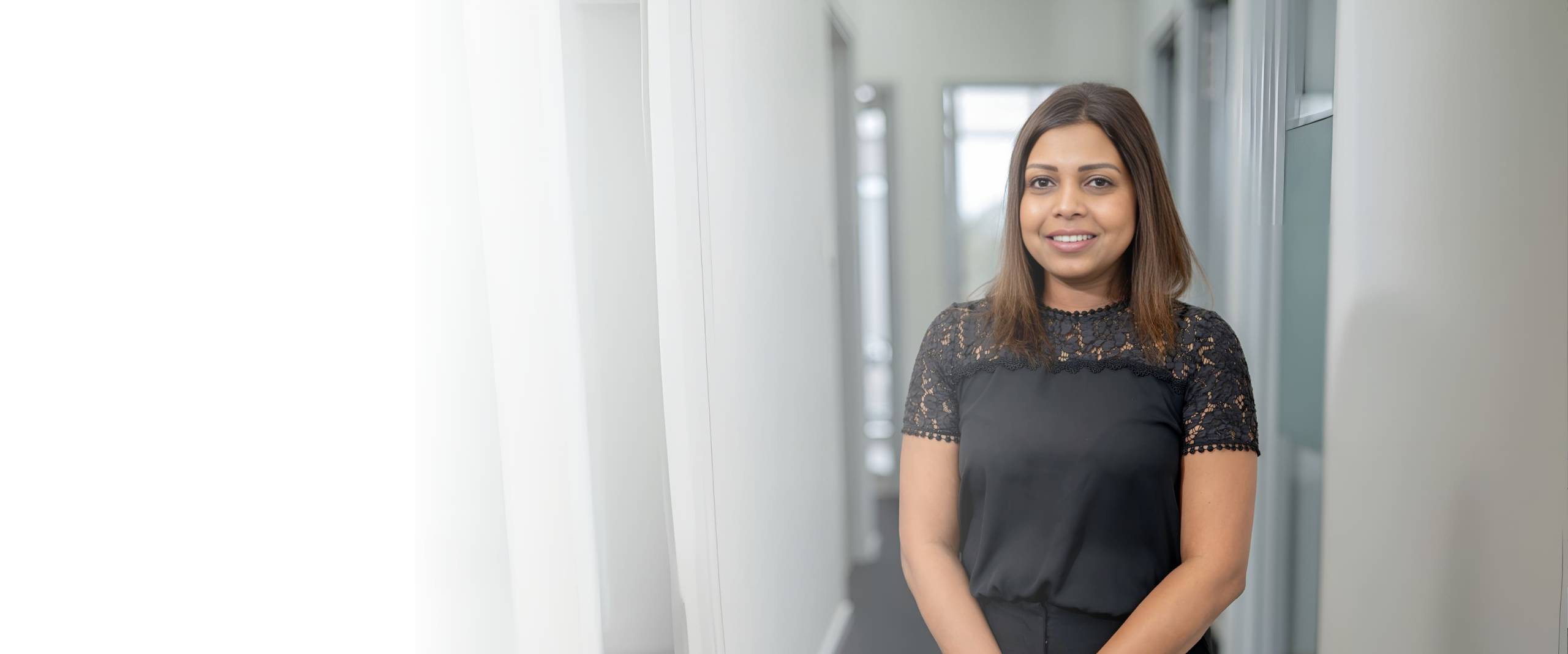 Professional female staff member smiling in a clinic hallway at Dandenong Dental Care for expert patient services.